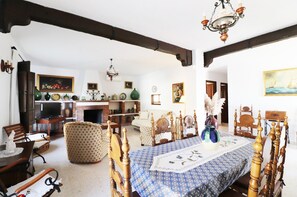 A traditional room with a wooden bed, a dining table, and a fireplace.
