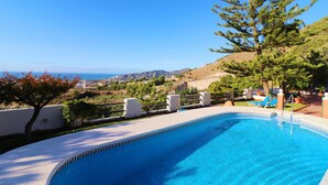Une piscine offrant une vue dégagée sur l’océan et les collines en arrière-plan.