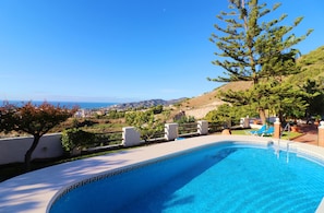 Una piscina con vista libera sull'oceano e colline sullo sfondo.