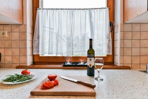 Eine Küchenarbeitsplatte mit Schneidebrett, Messer, Tomate, einer Weinflasche und einem Glas.