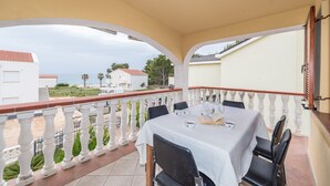 Un balcón con una mesa para dos, con vistas a una zona costera con edificios y árboles.