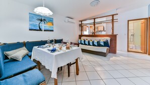 Un comedor con una mesa dispuesta para dos, un sofá azul y un banco con cojines.