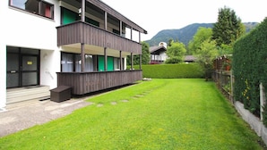 Ein zweistöckiges Gebäude mit einem Balkon, einem gepflegten Rasen und einem Berg im Hintergrund.