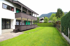 A two-story building with a balcony, a well-maintained lawn, and a mountain in the background. - Anne (Garmisch-Partenkirchen)