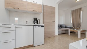 A modern kitchen with white cabinets, a dishwasher, and a coffee maker. - Apartments Simic (Vir)