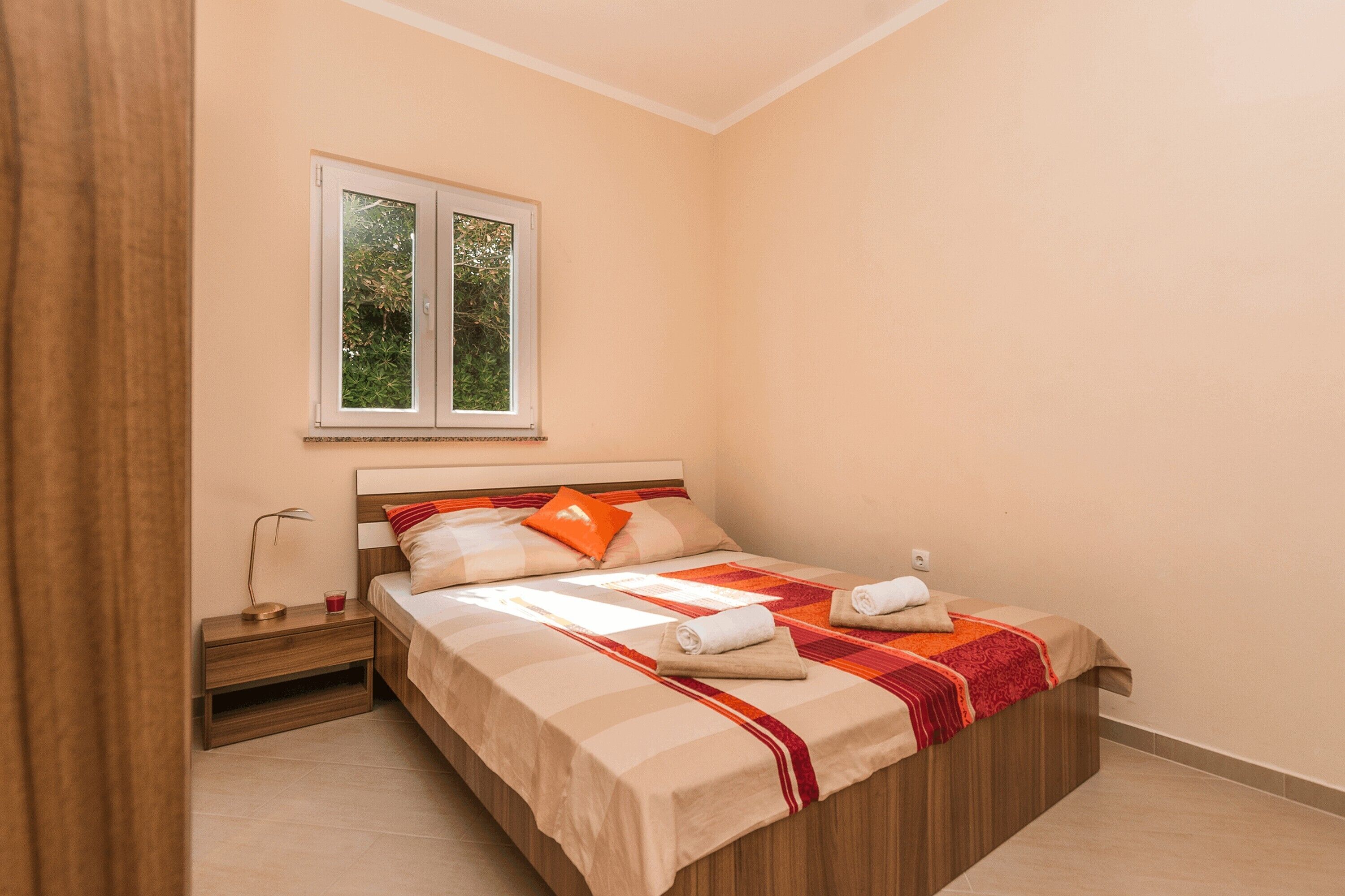 A bedroom with a bed, nightstand, and window.