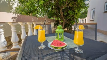 A table with two glasses of orange juice, a slice of watermelon, and a green lantern.