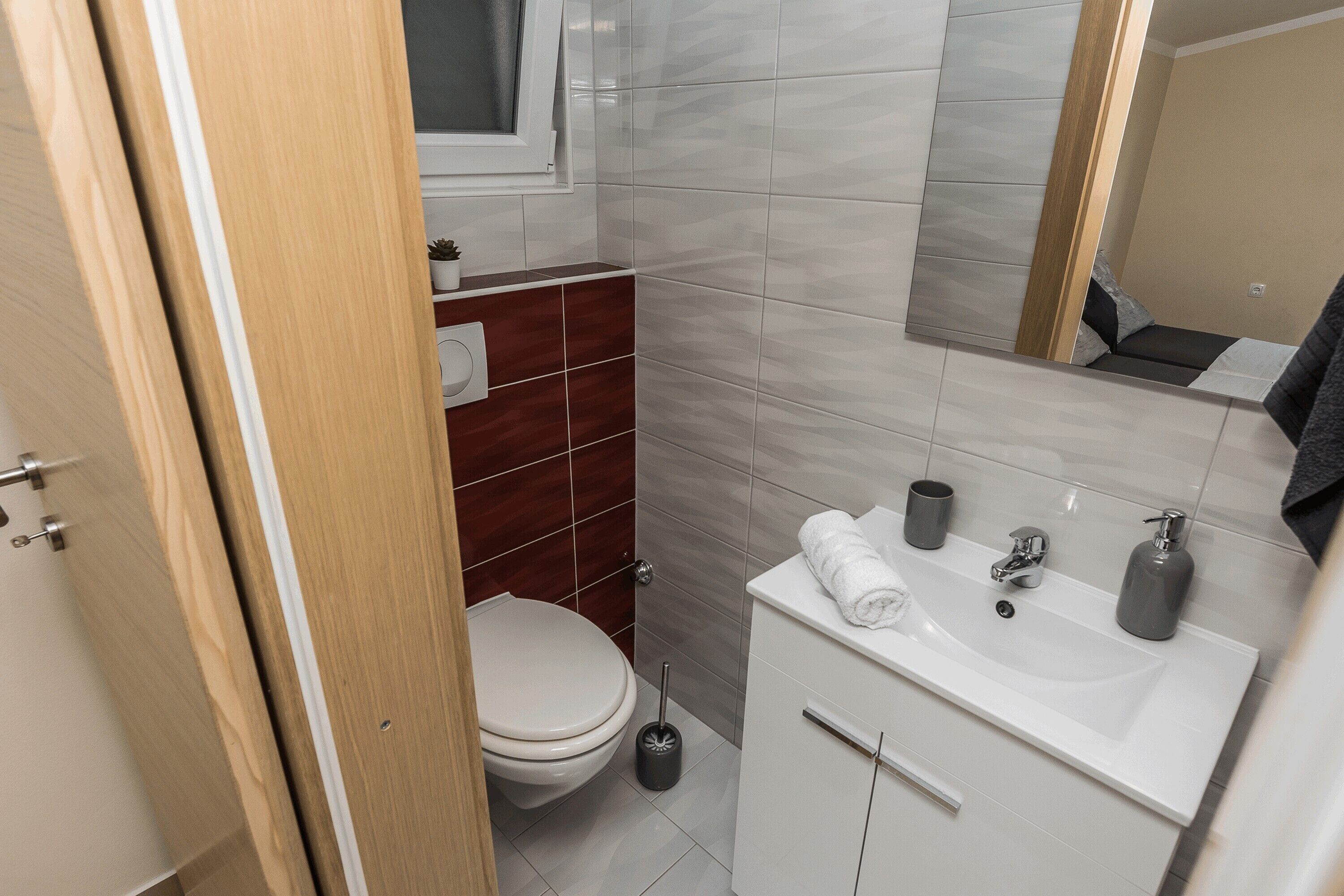 Un baño con inodoro, lavamanos y espejo.