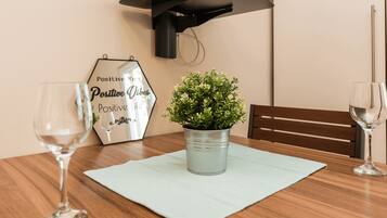 A dining table with a potted plant, two wine glasses, and a wall-mounted light fixture.