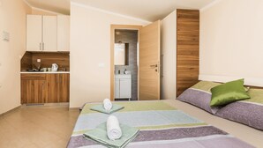 Ein kompaktes Hotelzimmer mit Bett, einer kleinen Küchenzeile und einem durchgegangenen Badezimmereingang.