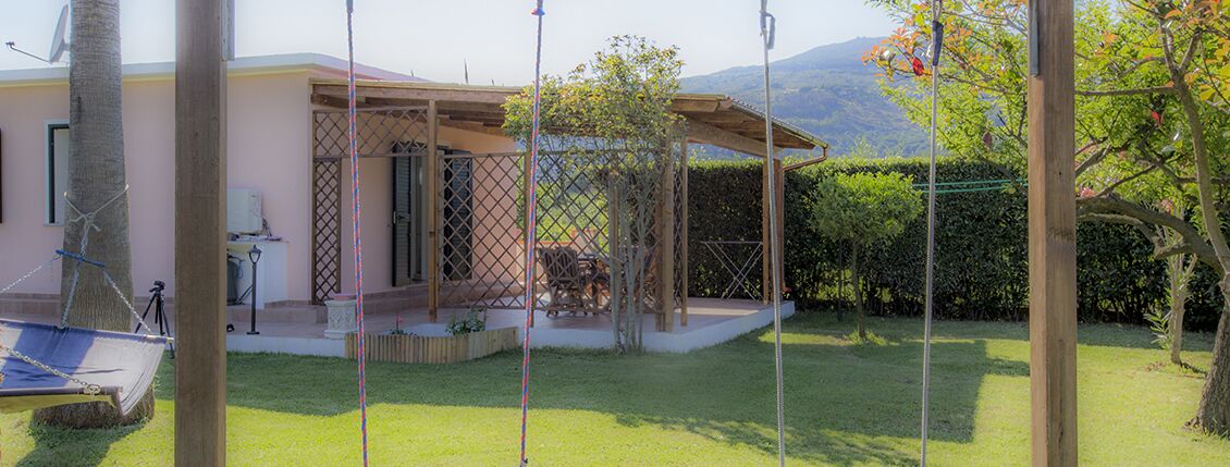 A house with a covered patio, a hammock, and a fenced garden area.