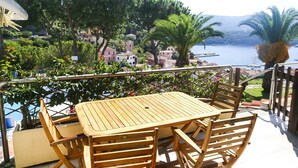 A wooden table and chairs on a balcony with a view of a coastal town and a body of water. - Il Porto Bilocale 13 (Porto Azzurro)