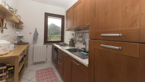 Cocina compacta con armarios de madera, horno empotrado, un lavamanos y ventana con vistas a la montaña.