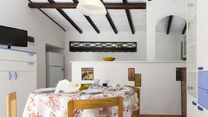 A compact kitchen with a dining area, a television, and a refrigerator. - Appartamento Casa Plein Air  (Portoferraio)