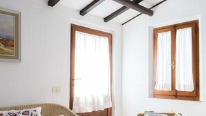 A room with a bed, a television mounted on the wall, and a window with curtains. - Appartamento Casa Plein Air  (Portoferraio)