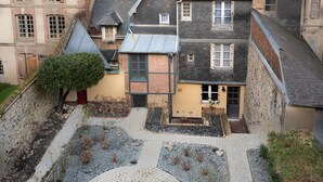 Un patio con un sendero adoquinado, un mosaico circular y edificios con fachadas de ladrillo y varias chimeneas.