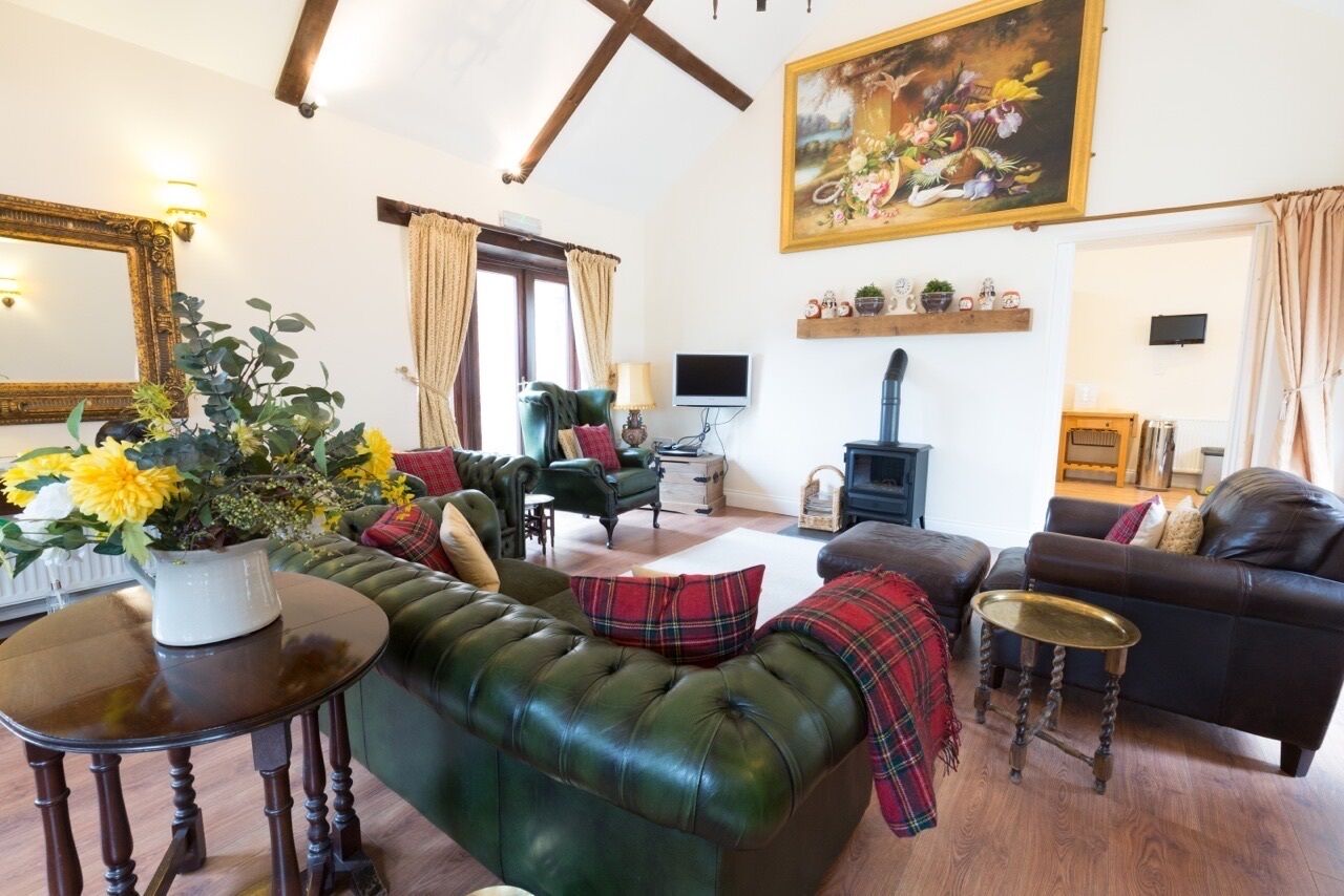 A cozy living room with a green sofa, a wooden coffee table, and a fireplace. There is a painting on the wall and a television on a stand.