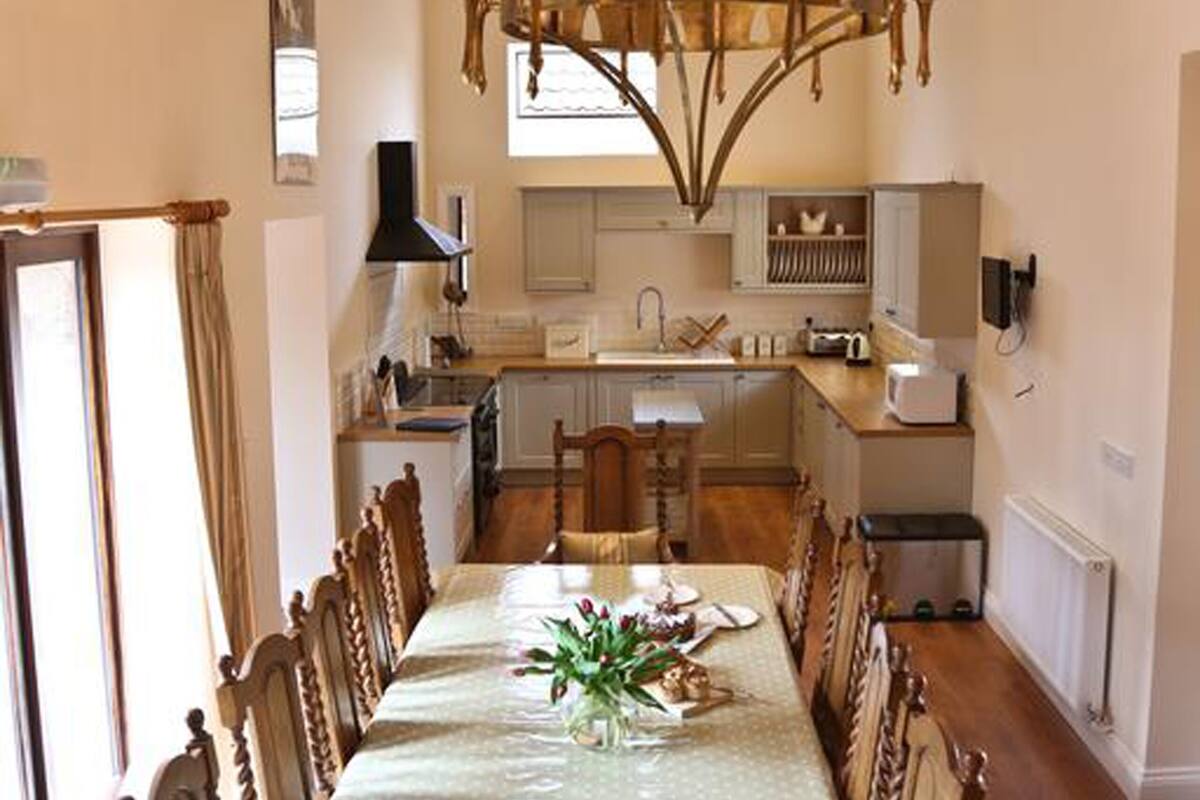 A dining area with a long table, wooden chairs, and a chandelier.