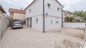 A two-story building with a gravel driveway and a parked car. - Apartment Banic (Vir)