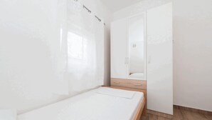 A bedroom with a single bed, a wooden wardrobe, and a mirror. - Apartment Banic (Vir)