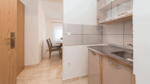 A modern kitchen with a built-in sink, wooden cabinets, and a dining area with a table and chairs. - Apartment Banic (Vir)
