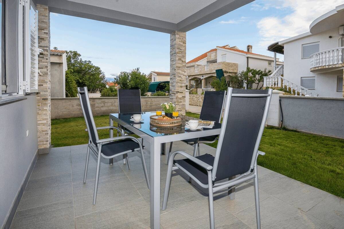 An outdoor patio with a table and chairs, a glass-top table, and a small fire pit.