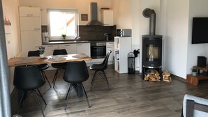 Una cocina moderna con una isla central, muebles blancos y estufa de leña.