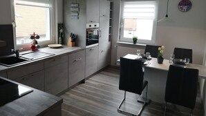 Een moderne keuken met een eethoek, met een ingebouwde oven, een spoelbak en een eettafel met stoelen.