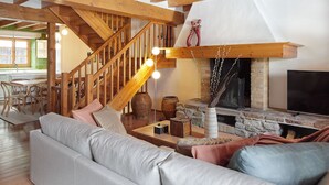 Un salon chaleureux avec un escalier en bois, une cheminée et un canapé.