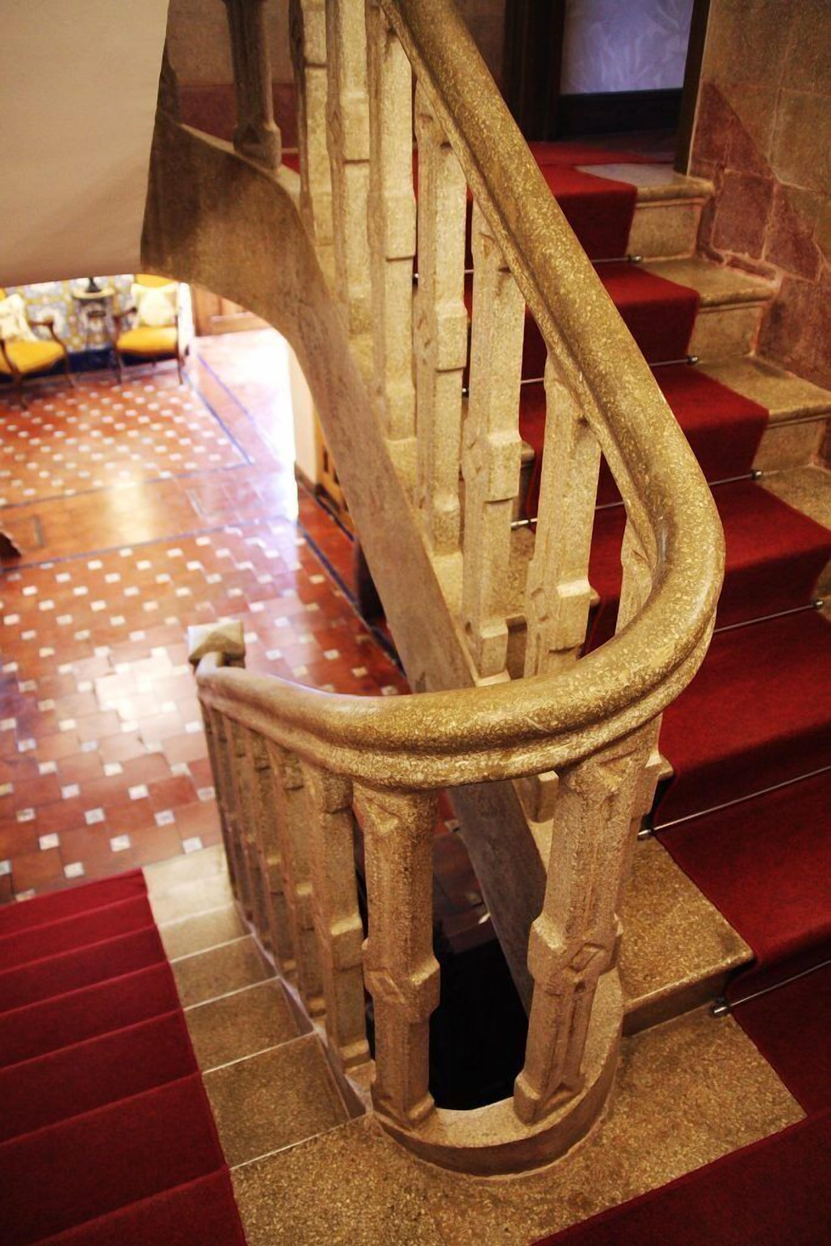 Una escalera con alfombra roja y barandilla dorada.