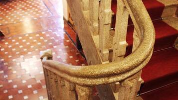 Una escalera con alfombra roja y barandilla dorada.