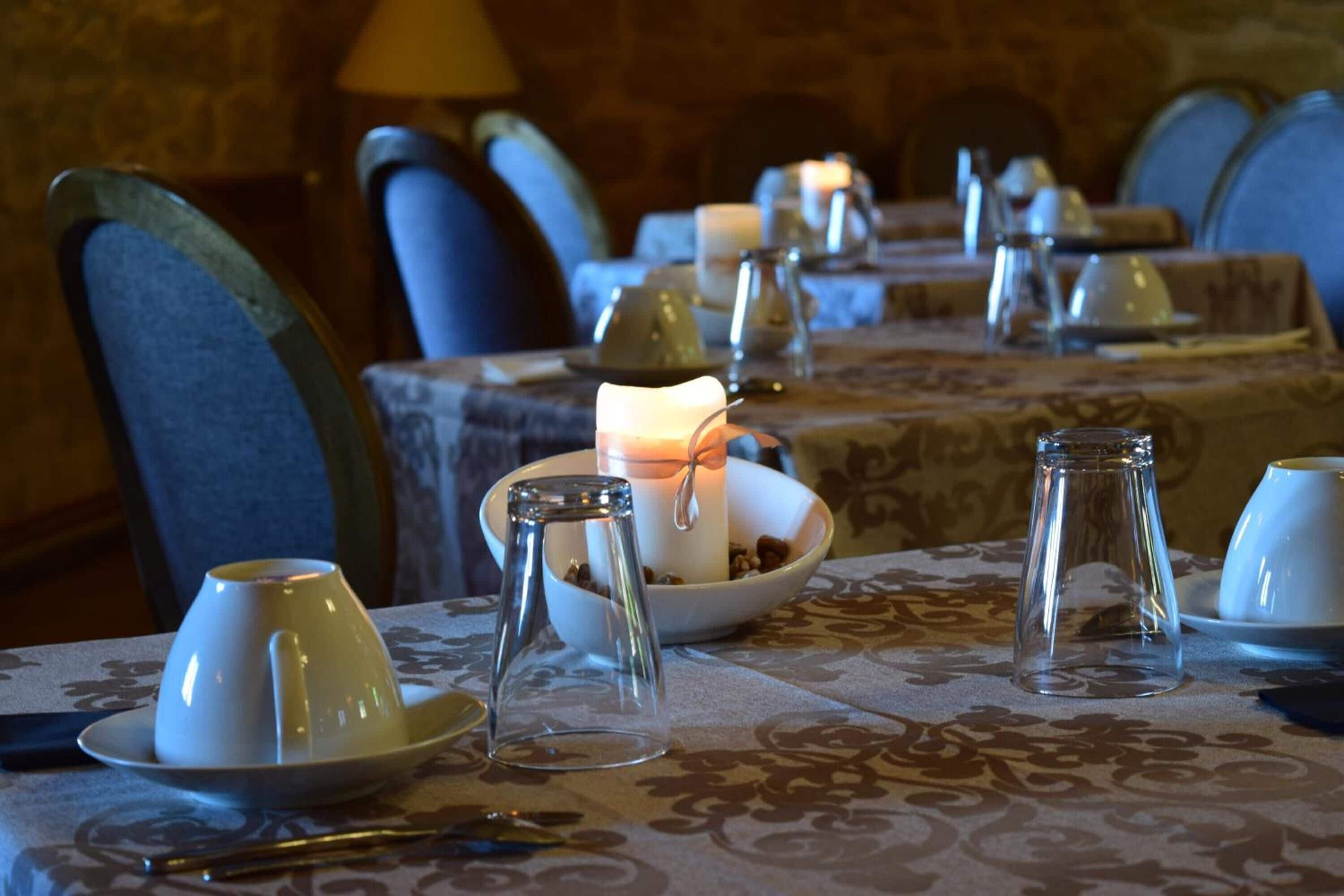 Une table à manger dressée avec de l’assiette blanche, des tasses et un chandelier servant de centre de table.