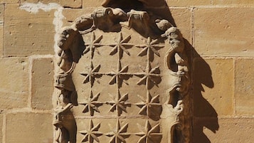 A stone wall with a carved emblem featuring a central figure and surrounding foliage.