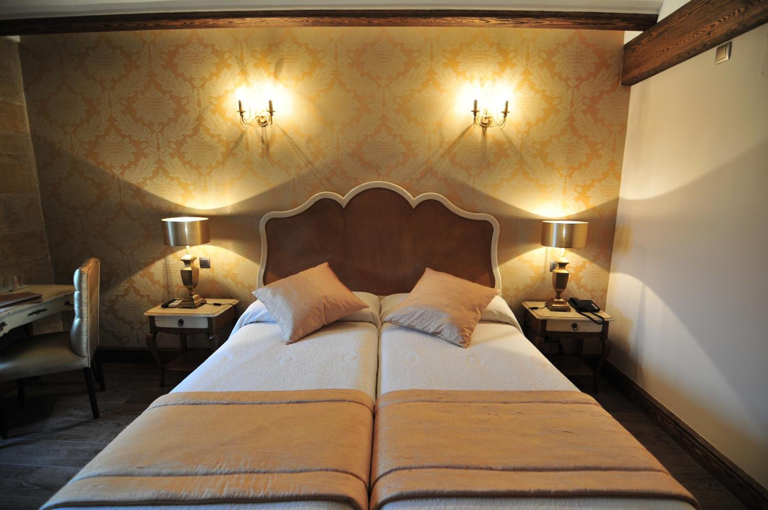 A double bed with a wooden headboard, two bedside tables with lamps, and a chair.