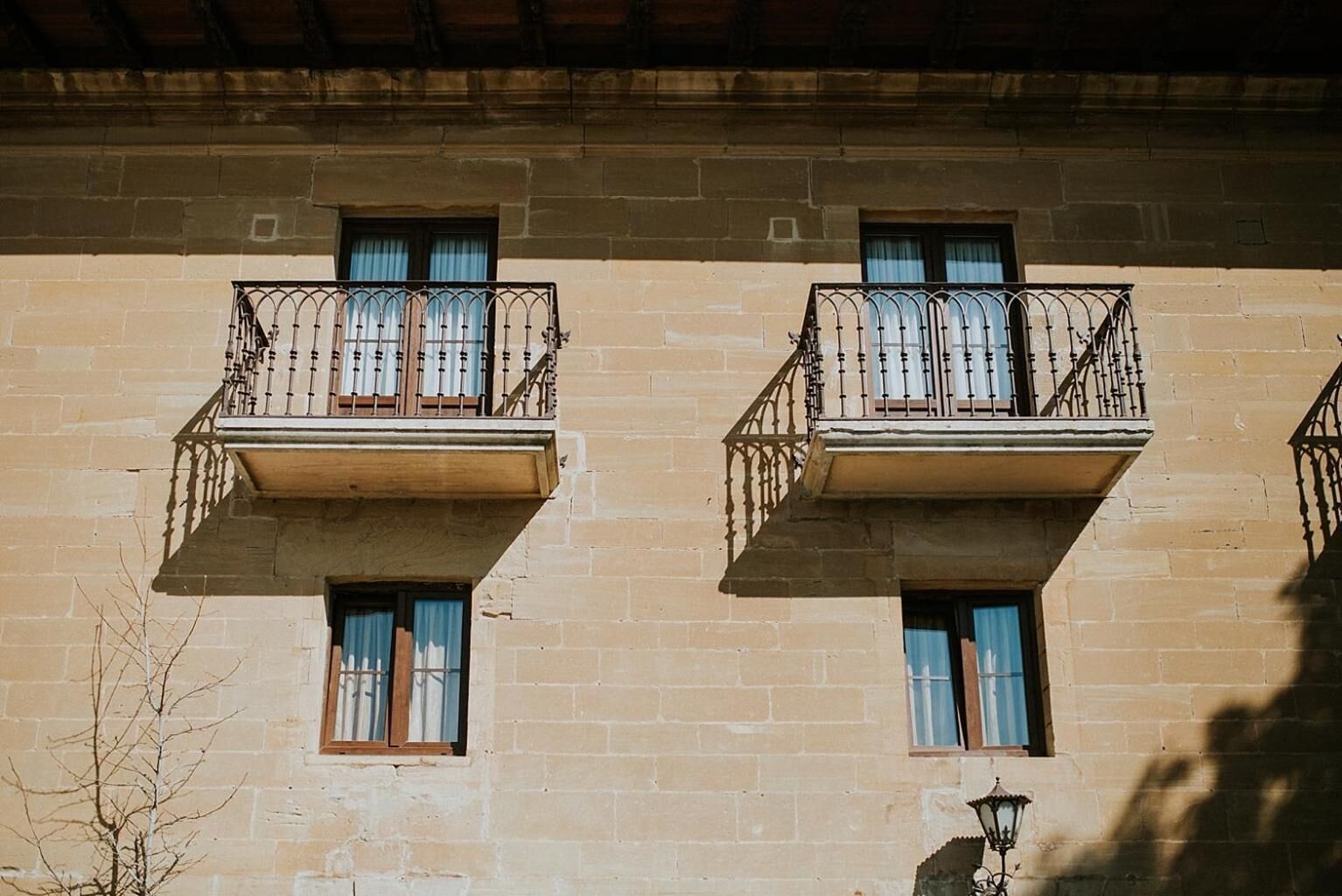 A building with two balconies, each with a wooden railing and a window.