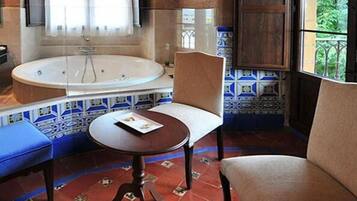 A bathroom with a bathtub, a chair, and a table.