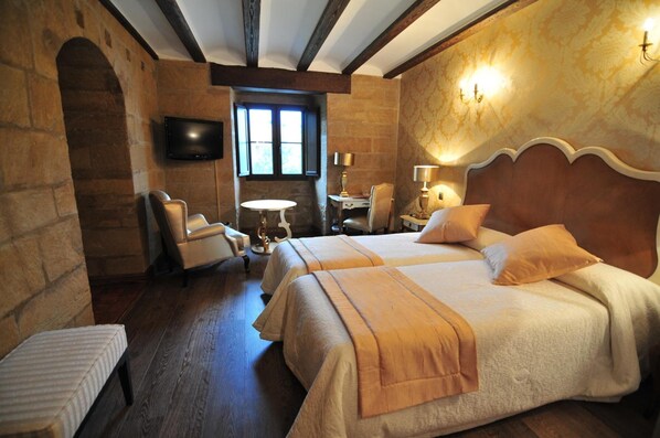 Habitación de hotel con dos camas, televisión, una mesita y una silla.
