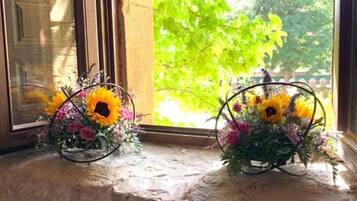 Una ventana con dos arreglos florales sobre un alféizar de piedra.