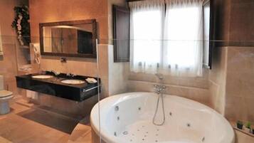 A bathroom with a large freestanding bathtub, a double sink vanity, and a large mirror above the vanity.