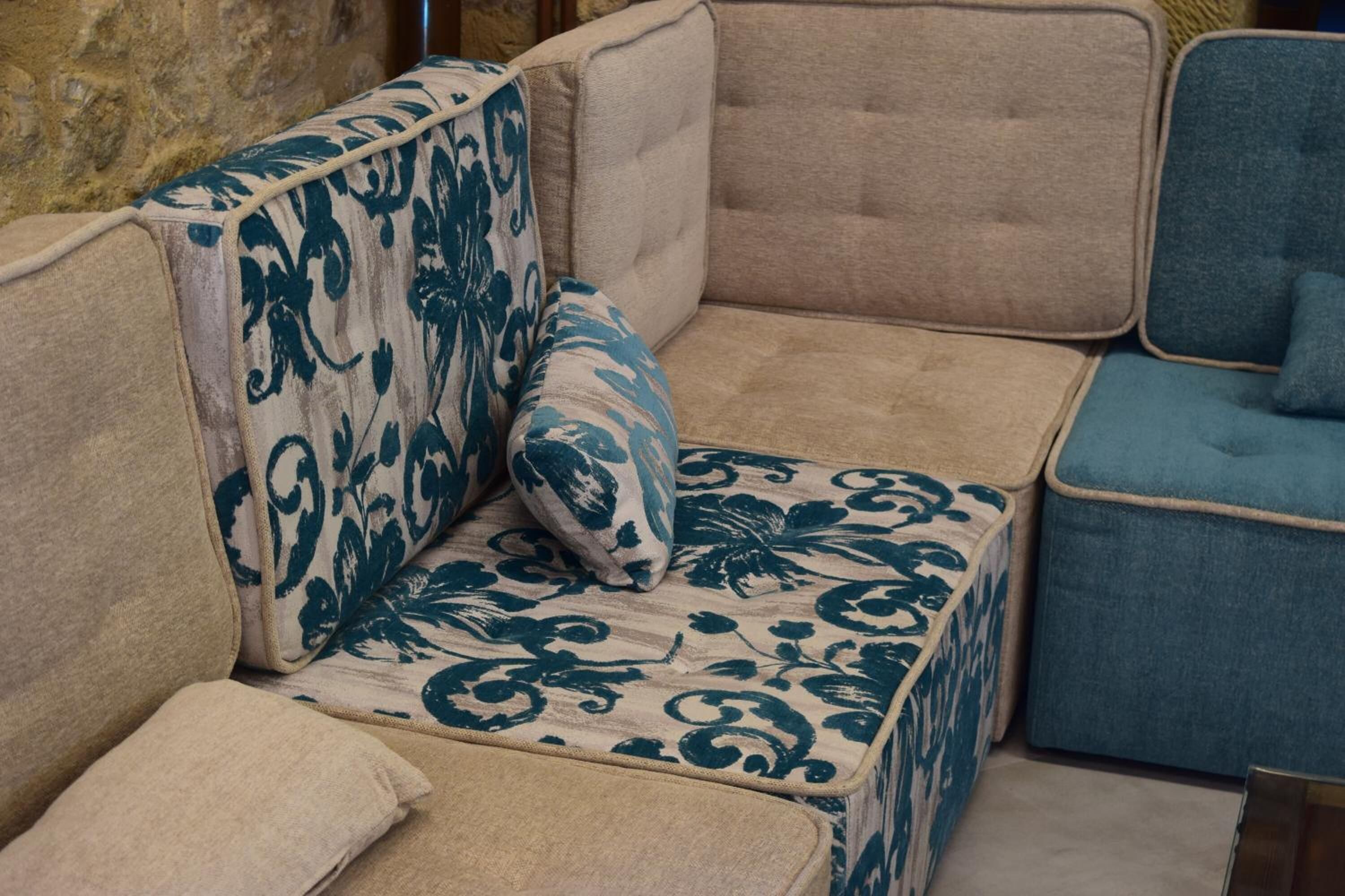 Un canapé d’angle à motifs floraux, un coussin assorti et un fauteuil bleu.