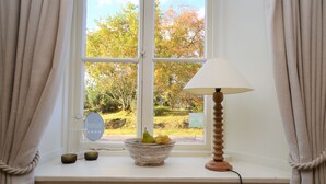 A window with a bowl of fruit, a lamp, and a mirror on a white ledge. - Darroch Beag Cottage, nearby Loch Fyne, peaceful location (St Catherines, Cairndow)