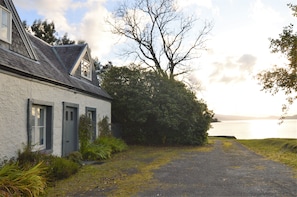 A house with a gravel driveway leading to a body of water.