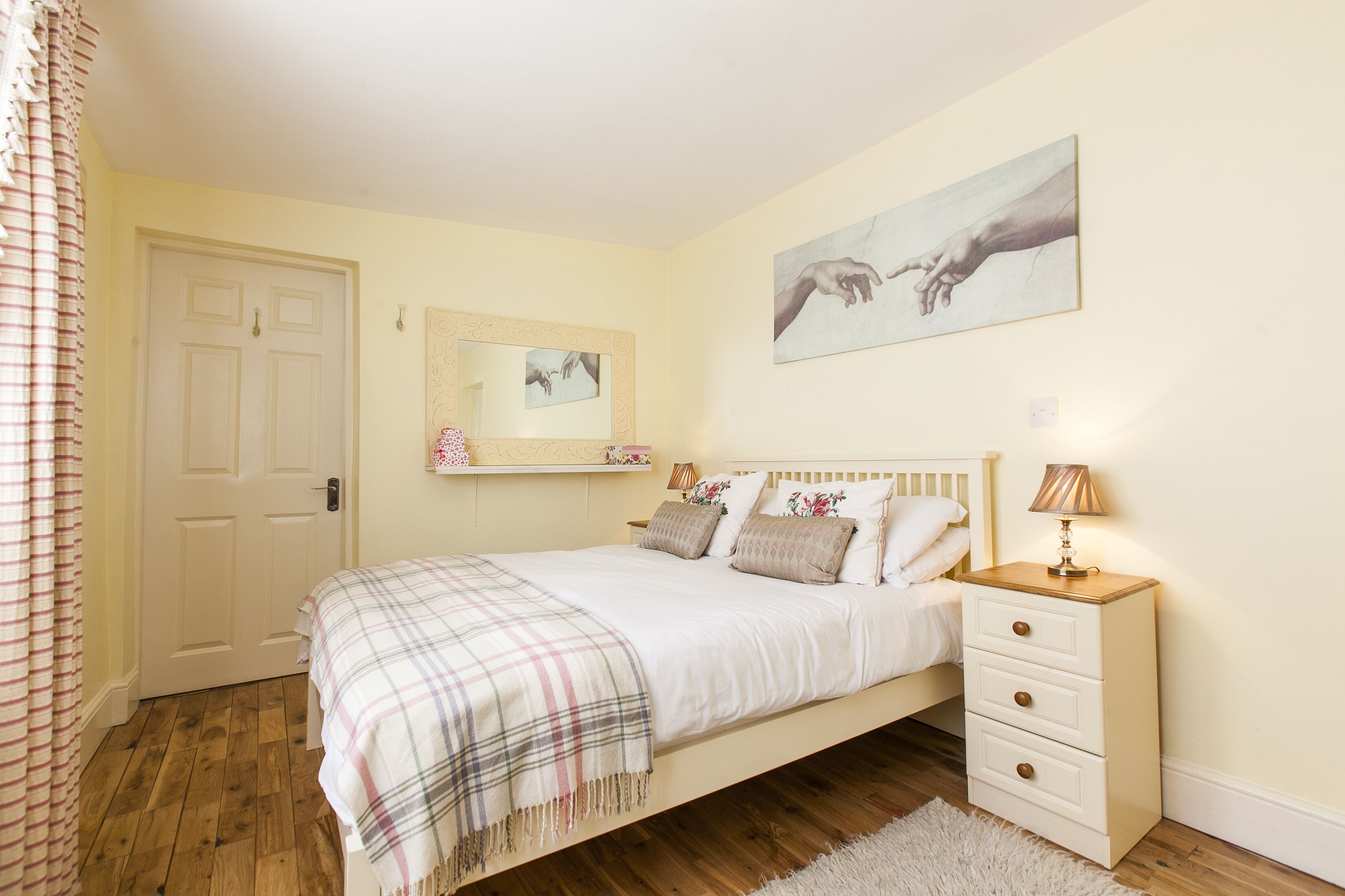 A bedroom with a bed, bedside table, and a mirror.