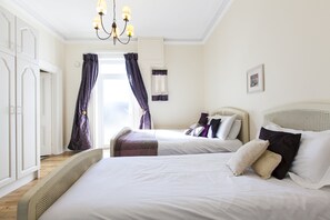 A bedroom with two beds, a chandelier, and a wardrobe.
