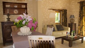 Un salon chaleureux avec une table à manger en bois, un canapé et une table basse. Un vase rempli de fleurs est posé sur la table.