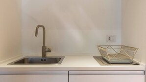 Une cuisine dotée d’un évier en acier inoxydable, d’un robinet moderne et d’un panier en fil métallique posé sur le plan de travail.