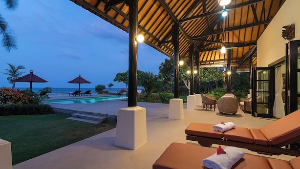 A covered outdoor area with lounge chairs, a pool, and a view of the sea. - Beachfront @ Lovina Beach, 8P, Private Pool, BBQ (Dencarik)
