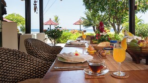 A table set with breakfast items, a glass of juice, and a view of the ocean. - Beachfront @ Lovina Beach, 8P, Private Pool, BBQ (Dencarik)