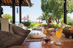 A table set with breakfast items, a glass of juice, and a view of the ocean. - Villa Namasté - Beachfront @ Lovina Beach, 10P, Private Pool, BBQ (Dencarik)