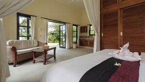 A bedroom with a large bed, a sofa, a small table, and a view of the outdoors through a sliding door. - Beachfront @ Lovina Beach, 8P, Private Pool, BBQ (Dencarik)